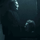 A man in face paint standing in a dark room with Michael Myers' iconic mask in front of him.
